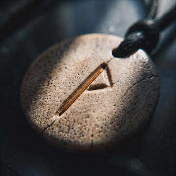 Carved wooden Thurisaz rune pendant with triangle symbol on black cord, close-up esoteric jewelry detail