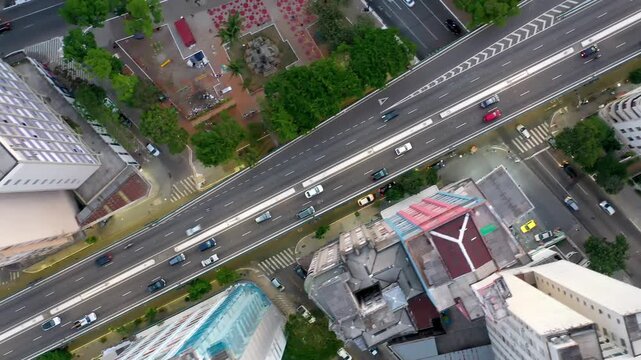 S&Atilde;O PAULO, BRASIL - 20 de AGOSTO DE 2025: Vista a&eacute;rea top-down de drone do tr&aacute;fego na Liga&ccedil;&atilde;o Leste-Oeste elevada passando sobre parque urbano e edif&iacute;cios antigos no centro