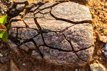 Mechanical weathering of a pink granite boulder under frost action. Concept of collapse, crisis and fragile structure shown by cracked rock © PhotoChur