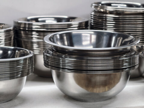 Stacked metal bowls with polished stainless finish displayed on supermarket shelves, highlighting kitchenware designed for durability and efficient everyday cooking use