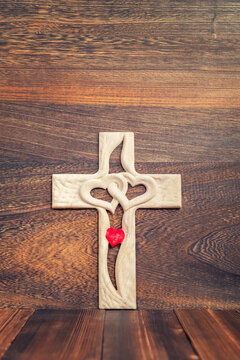 Wooden cross with a heart in the middle on wooden background