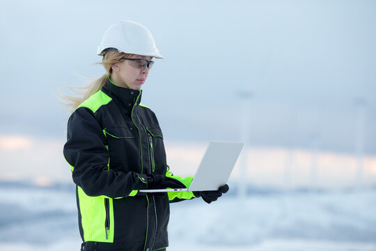 Woman in high visibility workwear using laptop in cold outdoor environment
