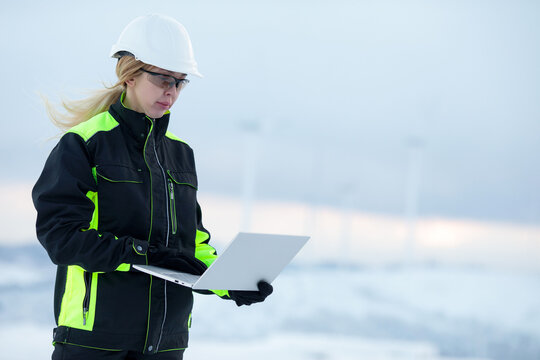 Woman engineer in hard hat using laptop in cold weather outdoor setting