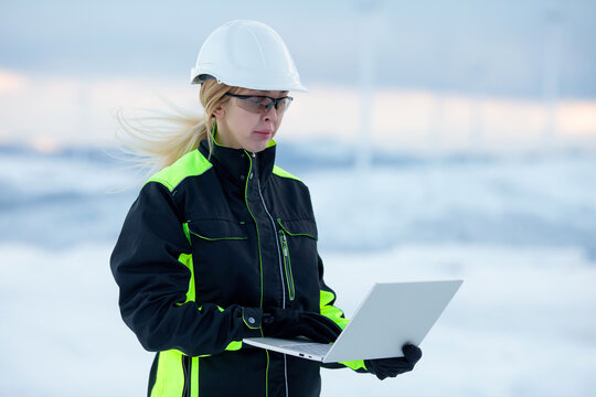 Woman engineer in safety gear using laptop in cold weather conditions