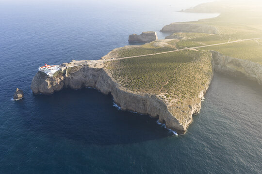 Aerial view of the Cabo de Sao Vicente lighthouse perched on a dramatic cliff edge overlooking the Atlantic Ocean in Portugal.