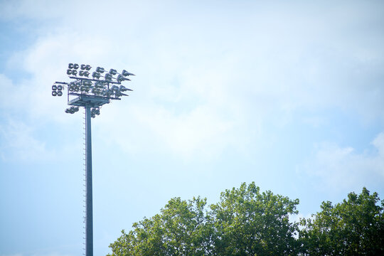 Stadium floodlights rise against a blue summer sky