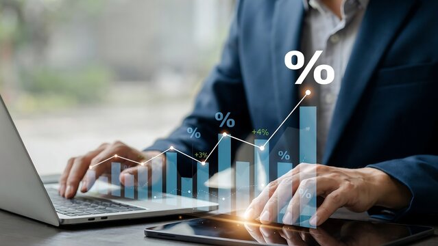 Businessman analyzing financial data growth and interest rates with digital charts on a laptop and tablet in a modern office setting
