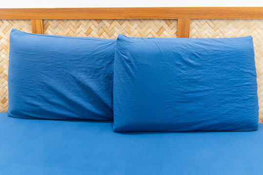 Two blue pillows arranged on a neatly made bed in a Vietnamese homestay, featuring a simple interior, woven headboard, and clean comfortable accommodation setting.