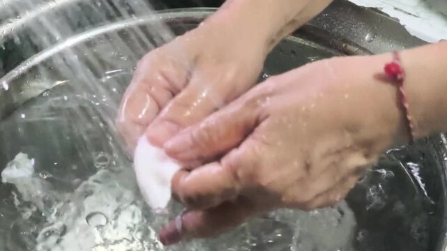 A woman is washing shrimp and other seafood with clean water in preparation for cooking Clean the squid thoroughly.