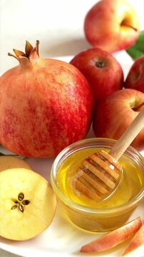 Happy Rosh Hashanah. Jewish New Year holiday concept. Honey dipper in a bowl with honey, next to apples, shofar horn and pomegranates.