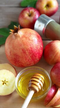 Happy Rosh Hashanah. Jewish New Year holiday concept. Honey dipper in a bowl with honey, next to apples, shofar horn and pomegranates.
