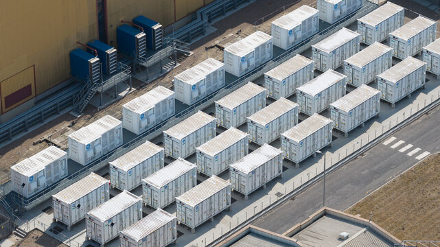 Aerial view of the Brigg Renewable Energy Plant featuring rows of white battery storage containers arranged on a paved industrial site in Scawby, England, United Kingdom.