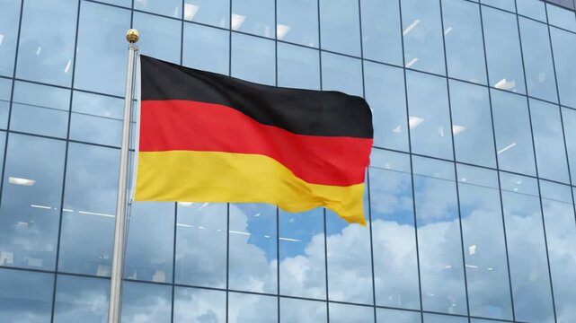 German flag waving in wind against modern glass office building facade national symbol of germany