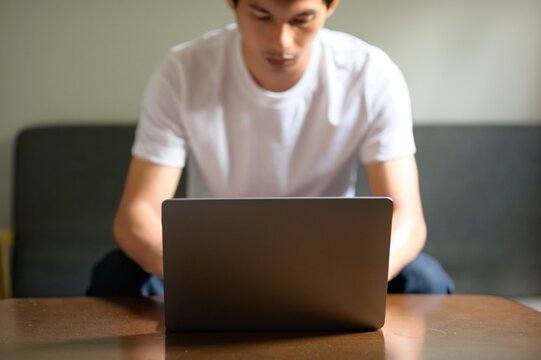 Young Man Using Laptop at Home, Focused on Work or Study