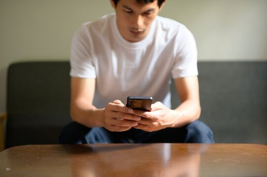 Young Man Engaged with Smartphone in Casual Indoor Setting