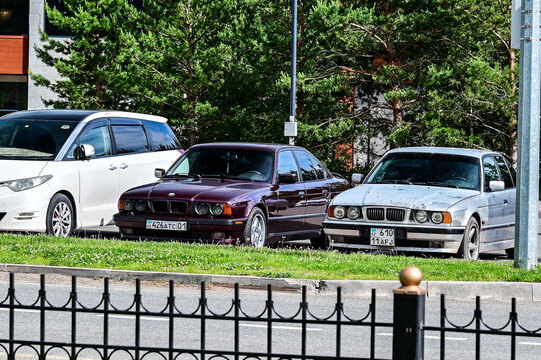 Two 1990s BMW 5 Series E34 sedans&mdash;one Bordeaux red and the other silver, both with Kazakh license plates&mdash;are parked in Burabai; classic German vintage cars, Akmola Region, Kazakhstan 17.05.25