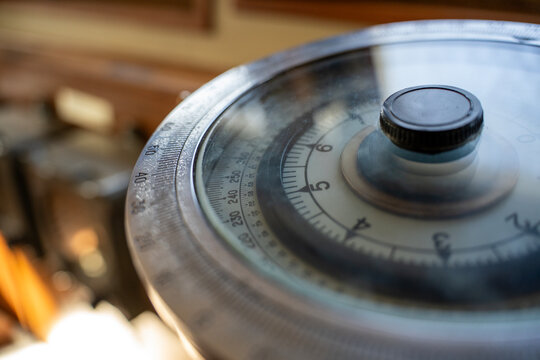 Close up of vintage nautical gyrocompass navigation instrument with circular degree scale dial on ship bridge indoors.
