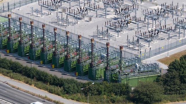 Aerial view of an industrial power plant featuring a row of green generator units with exhaust stacks and electrical substation infrastructure in Immingham, England, United Kingdom.