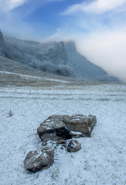 Misty mountain landscape with snow-covered rocks and frosted trees