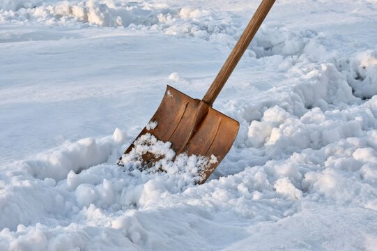Shovel clearing snow from path during winter day