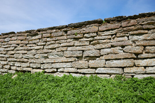 Ancient old limestone wall in mansion park with blue sky and lush green vegetation in Estonia