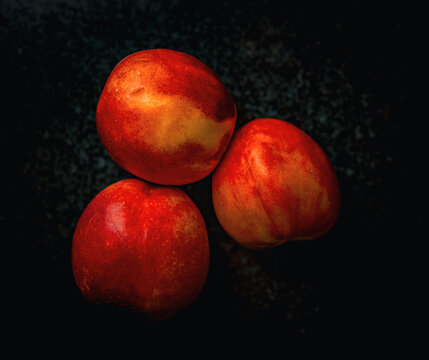 Three ripe peaches on a dark background