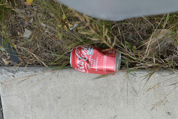 Naklejka premium slightly crushed discarded can of Coca-Cola on the ground by a curb in Toronto