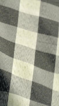 Close-up of black and white checkered fabric swaying gently in the wind, traditional Balinese poleng cloth pattern background texture