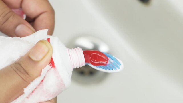 Close up hand holding applying toothpaste to toothbrush, isolated on sink background. brushing teeth daily in morning and evening. Dental health care and hygiene concept.