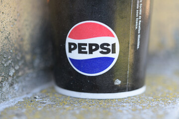 Naklejka premium detail of a discarded beverage cup with circular red, white, and blue emblem of the Pepsi Globe; bold brand name, Toronto