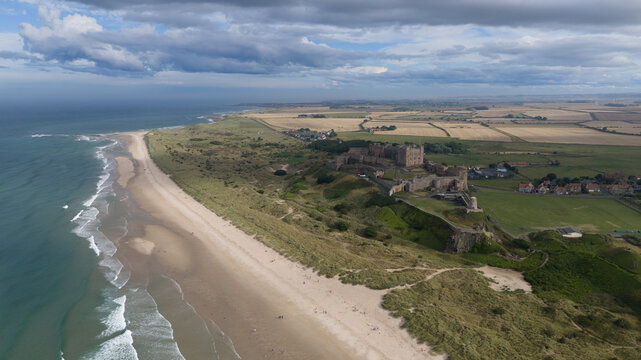 Aerial view of Bamburgh Castle perched on a rocky outcrop overlooking the sandy beach and the North Sea coastline in Bamburgh, England, United Kingdom.