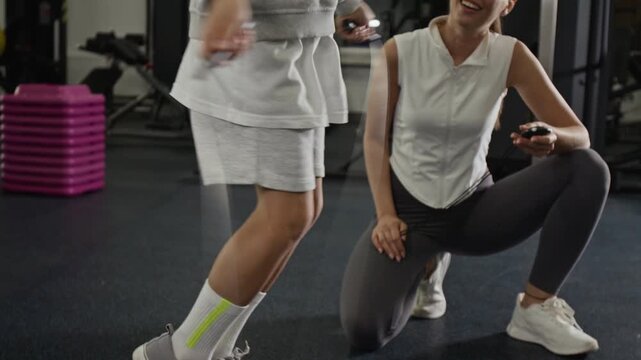 Caucasian child jumping rope during fitness training with female coach holding stopwatch, tilt up. Footage ideal for youth sports programs and healthy lifestyle advertisements