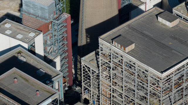 Aerial view of the industrial structures and cooling tower of Kraftwerk Voerde, featuring steel framework, flat rooftops, and long shadows in Voerde, North Rhine-Westphalia, Germany.