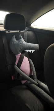 Handmade toy wolf with seatbelt in car back seat. Funny stuffed animal passenger. Humor, routine lifestyle 