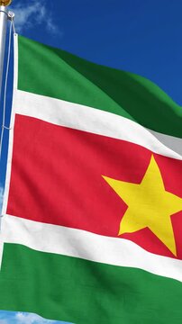 Suriname flag waving slowly on a flagpole against a clear blue sky