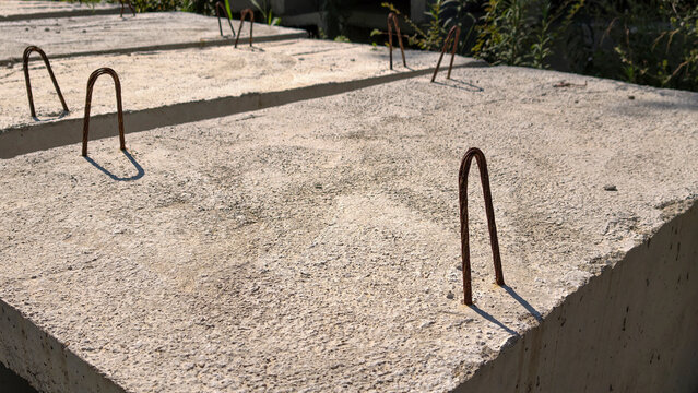 Precast concrete slabs with projecting rusted u shaped rebar anchors, showing reinforcement and connection points on an industrial construction site, textured and unfinished
