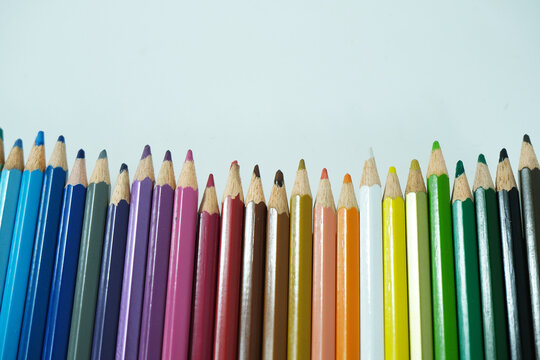 Colored pencils on a white background. Multicolored pencil background. Back to school. Learning tools.
