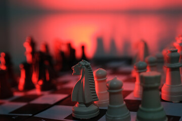 Close-up of a chess piece on a chessboard in dim red light. World Chess Day. International Chess Day. July 20.  © PANCASONA CREATION