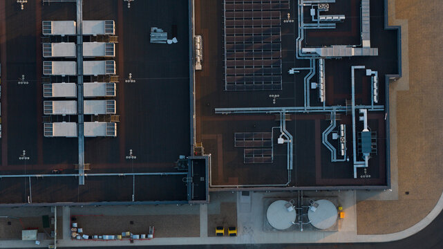 Aerial view of an industrial building roof featuring rows of HVAC units, solar panels, and ventilation systems in Bracknell, England, United Kingdom.