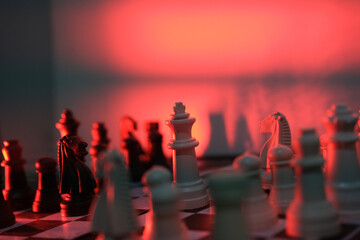 Close-up of a chess piece on a chessboard in dim red light. World Chess Day. International Chess Day. July 20.  © PANCASONA CREATION