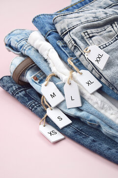 Various clothing sizes XS, S, M, L, XL on white wooden tags with jeans.