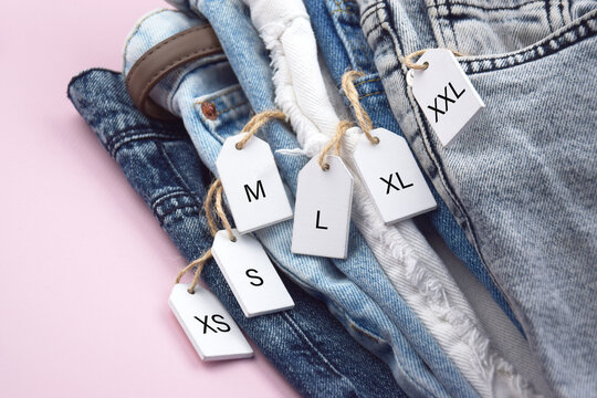 Various clothing sizes XS, S, M, L, XL on white wooden tags with jeans.