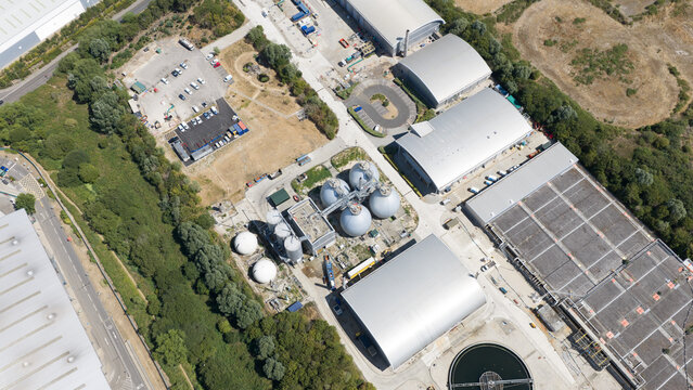 Aerial view of an industrial water treatment facility with large spherical tanks, processing buildings, and a circular sedimentation tank in Reading, England, United Kingdom.