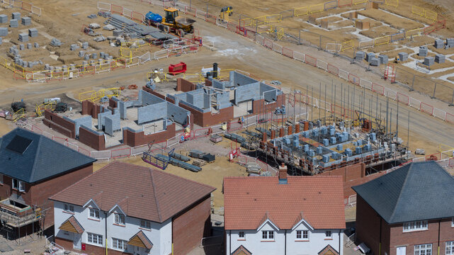 Aerial view of a residential construction site featuring brick foundations, building materials, and newly built houses in Basingstoke and Deane District, England, United Kingdom.