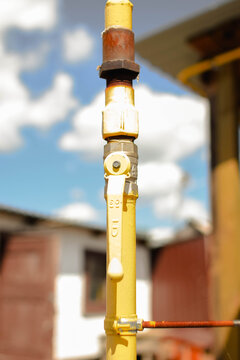 Gas shutoff valve on a vertical yellow gas pipeline with corroded metal fittings