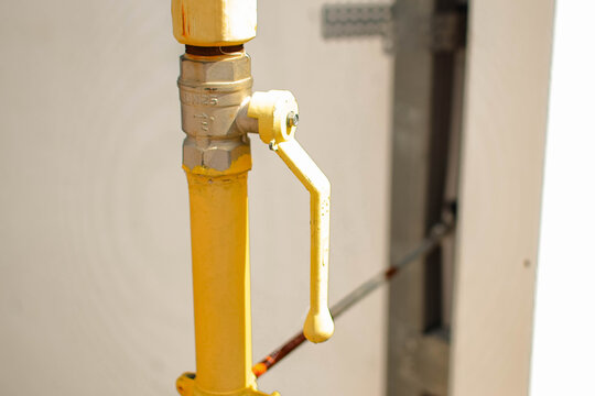 DN25 brass ball valve on a vertical yellow gas pipeline beside a building