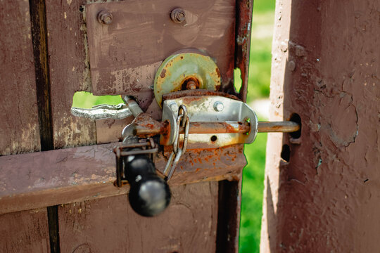 Homemade rusty gate locking mechanism with a heavy black lever handle