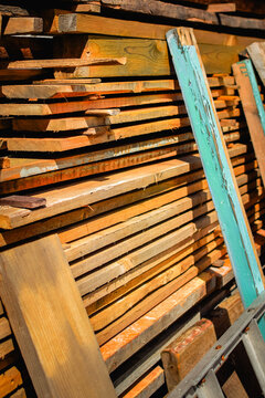 Large stack of old wooden boards and construction lumber in a rustic farmyard