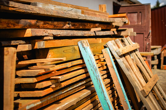 Large storage stack of old lumber and wooden construction materials in a rural yard