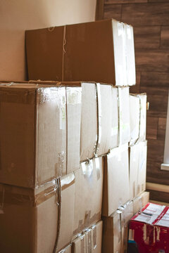 Stack of sealed cardboard moving boxes indoors, illustrating packing, relocation, transportation, household storage and moving preparation